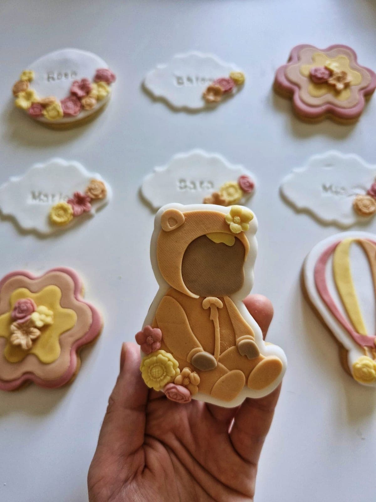 Les mains d’Agathe tenant un biscuit sablé en forme d’ourson décoré en pâte à sucre